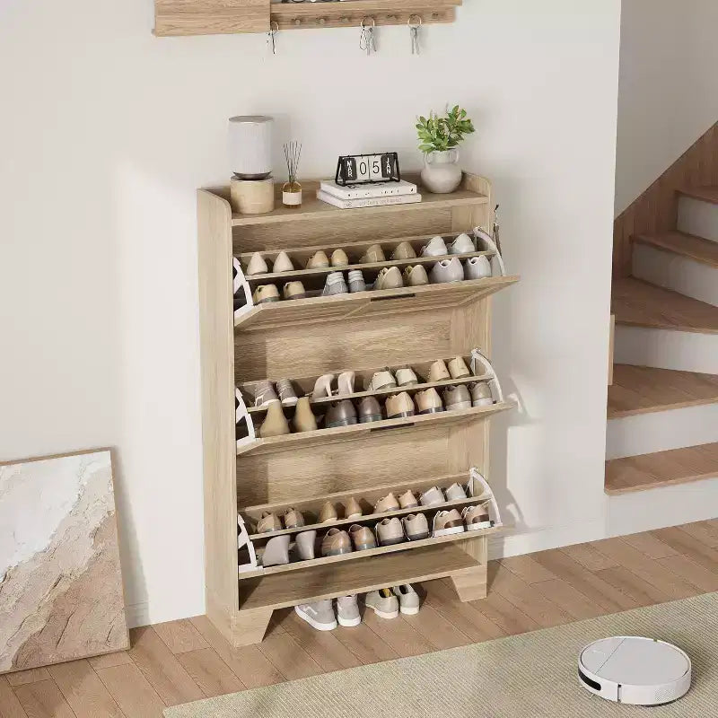 Meuble à chaussures autoportant avec 3 portes basculantes. Rangement dissimulé pour entrée, peut contenir plusieurs paires, style ferme avec crochets latéraux.