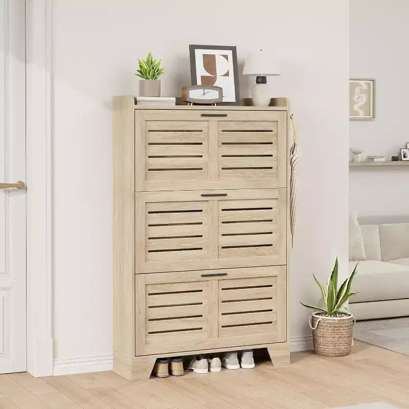 Meuble à chaussures autoportant avec 3 portes basculantes. Rangement dissimulé pour entrée, peut contenir plusieurs paires, style ferme avec crochets latéraux.