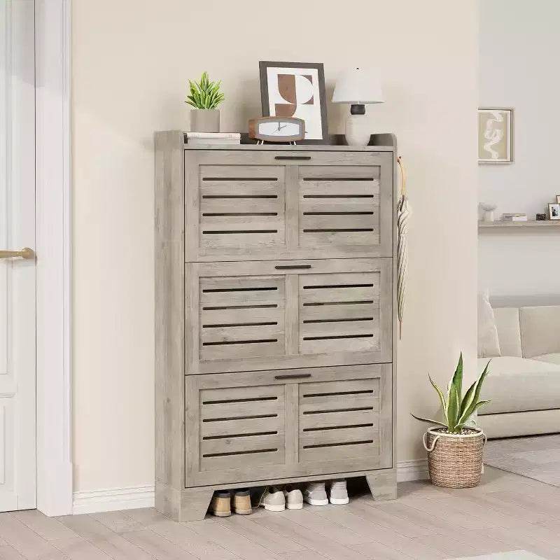 Meuble à chaussures autoportant avec 3 portes basculantes. Rangement dissimulé pour entrée, peut contenir plusieurs paires, style ferme avec crochets latéraux.